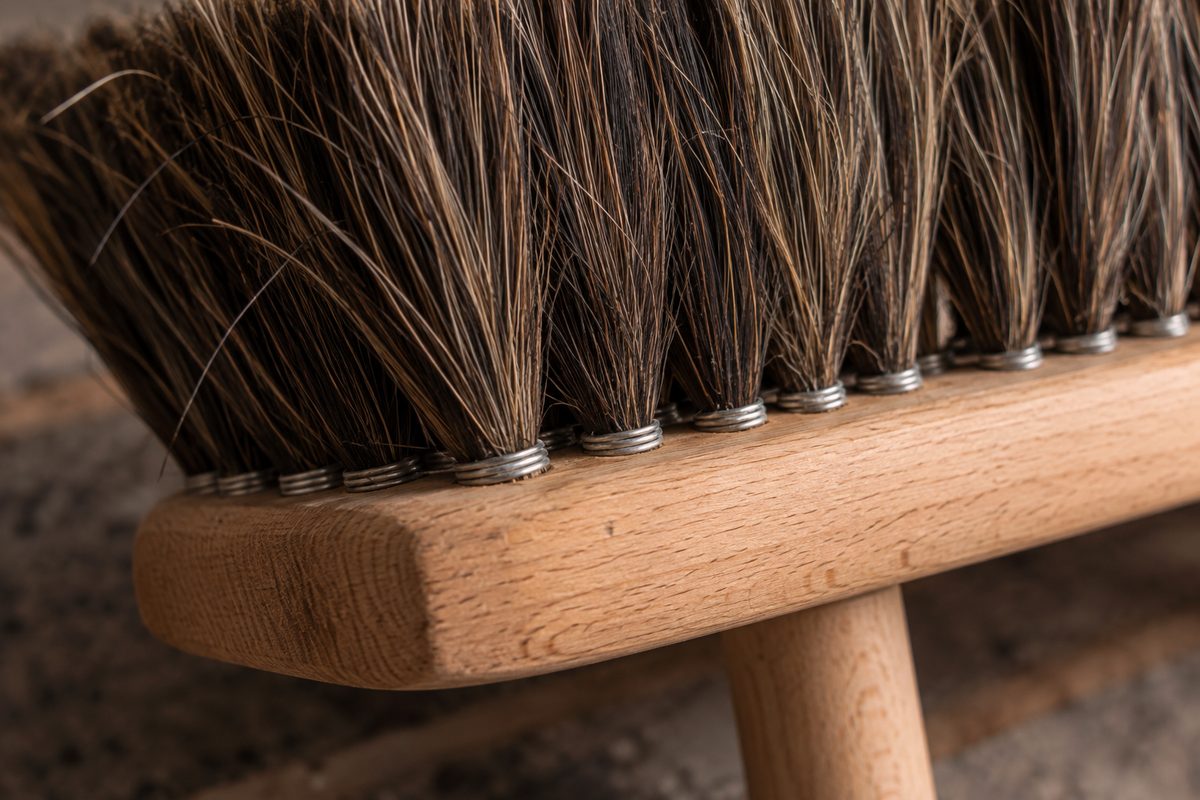 Macro texture of dense natural horsehair bristle tufts set into a sanded beechwood block.